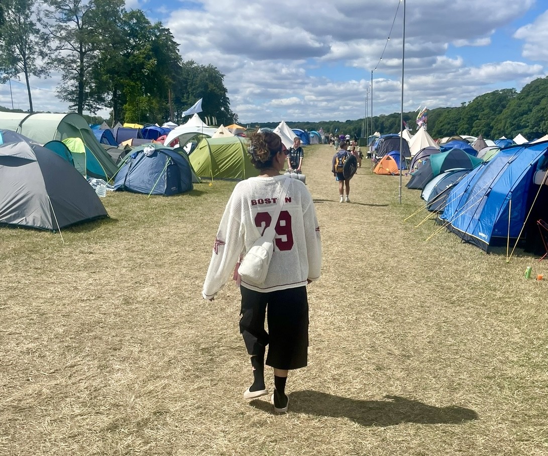 Festival For You team walking through the Wilderness Festival campsite on a sunny summer day, showcasing the camping culture and outdoor lifestyle of UK music festivals 2025.